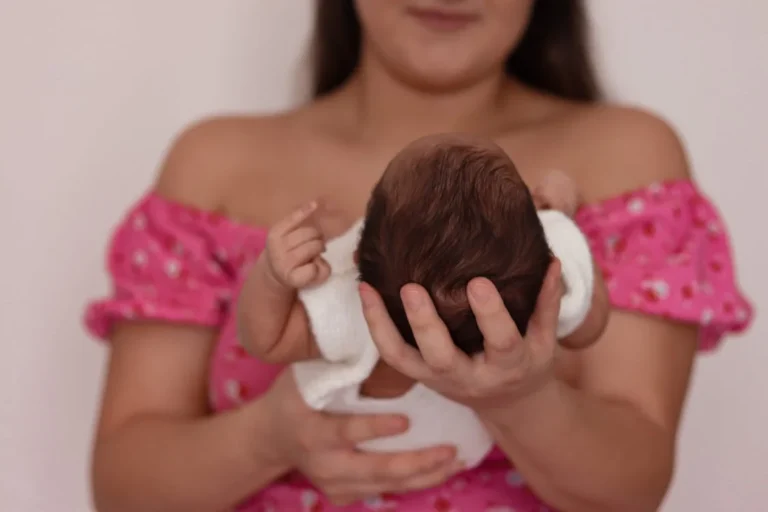 Mother holding and looking at her sleeping infant snoring